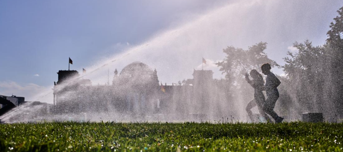 Lawn by the Reichstag being watered, runners passing
